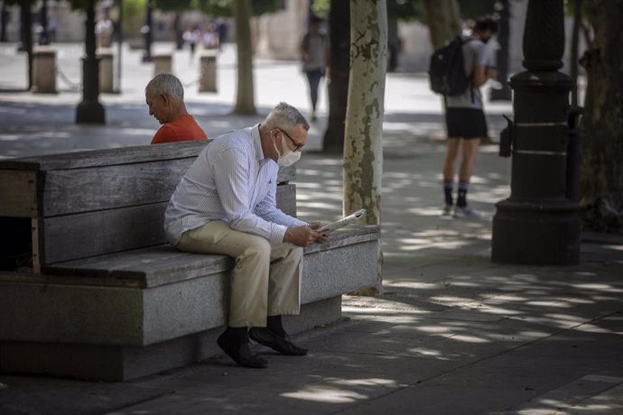 Archivo - Un hombre con mascarilla lee el periódico en Sevilla (Andalucía, España), a 29 de mayo de 2020.