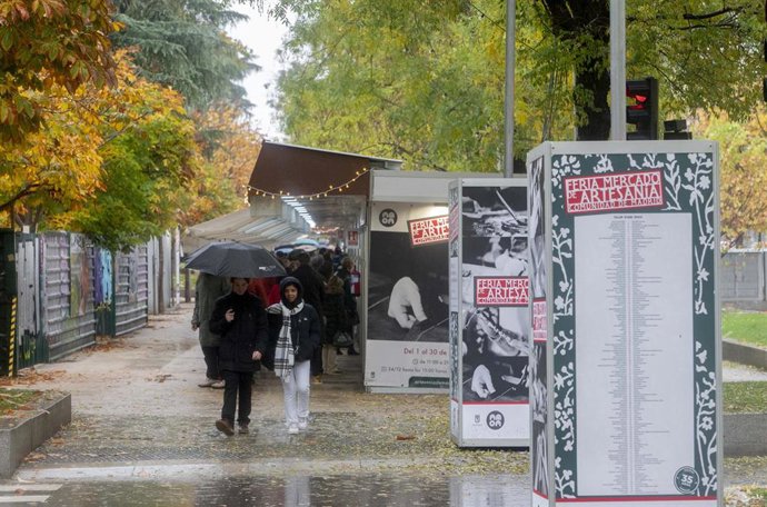 Varias personas visitan los puestos en la 36 edición de la Feria Mercado de Artesanía,  a pesar de la lluvia, en el Paseo de Recoletos, a 8 de diciembre de 2022, en Madrid (España). El Mercado de Artesanía, el más importante en España del sector, se ce