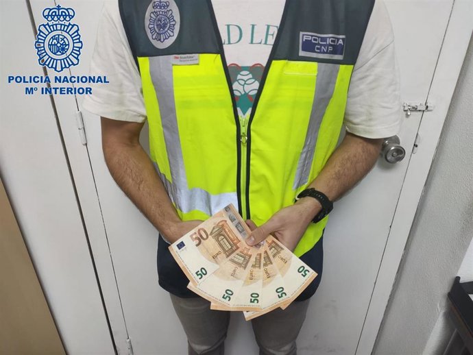 Un agente de la Policía muestra los billetes falsos con los que el joven detenido compró artículos en puestos ambulantes navideños en Palma