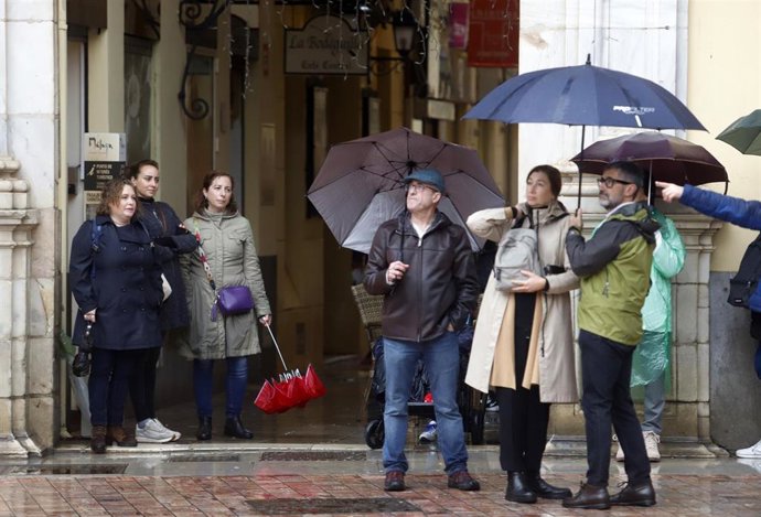 Varias personas se protegen de la lluvia bajo sus paraguas.