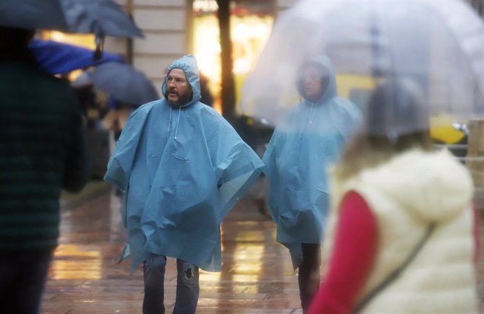 Varias personas se resguardan con paraguas. A 9 de diciembre de 2022 en Málaga, Andalucía. La borrasca deja ya más de 60 litros en la provincia de Málaga y la Agencia Estatal de Meteorología, Aemet rebaja a amarillo el aviso naranja por fuertes lluvias 