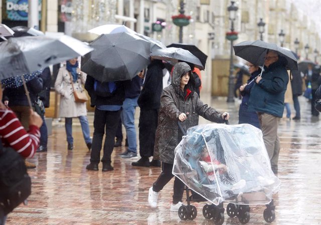 Varias personas se resguardan con paraguas. 