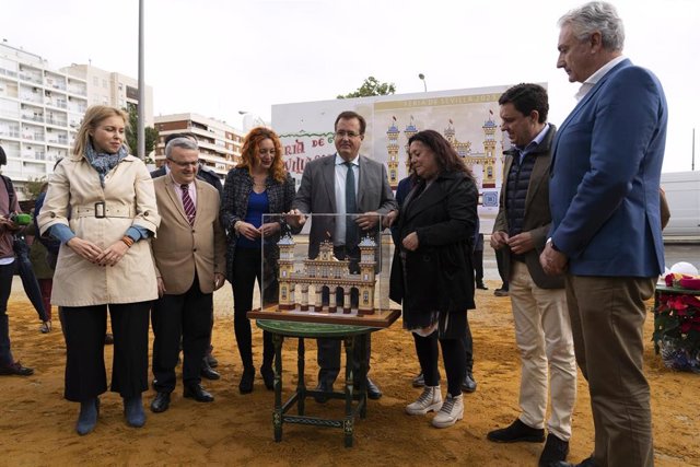 El delegado de Fiestas Mayores del Ayuntamiento de Sevilla, Juan Carlos Cabrera, (4i) junto a la maqueta de la Portada durante la colocación del primer tubo de la Portada de la Feria de Sevilla.