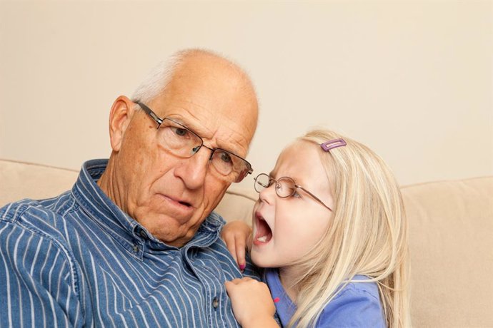 Archivo - Niña hablando al oido de su abuelo sordo.