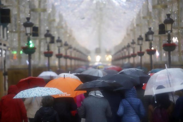 Varias personas se resguardan con paraguas. A 9 de diciembre de 2022 en Málaga, Andalucía.