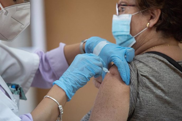 Archivo - Una enfermera vacuna a una mujer contra la gripe y el Covid en una foto de archivo.