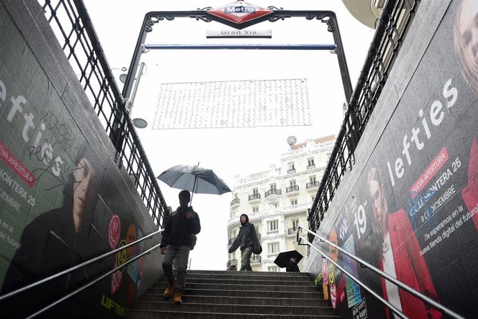 Personas entran al metro con paraguas y mojadas por la lluvia, a 13 de diciembre de 2022, en Madrid
