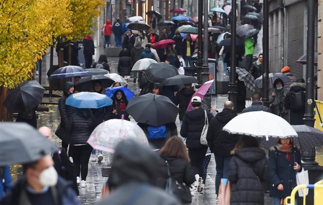 Personas caminan por la calle con paraguas, a 13 de diciembre de 2022, en Madrid (España). La previsión de la Agencia Estatal de Meteorología (Aemet) en la Comunidad de Madrid para hoy apunta a que las lluvias persistirán y que las temperaturas aumentarán