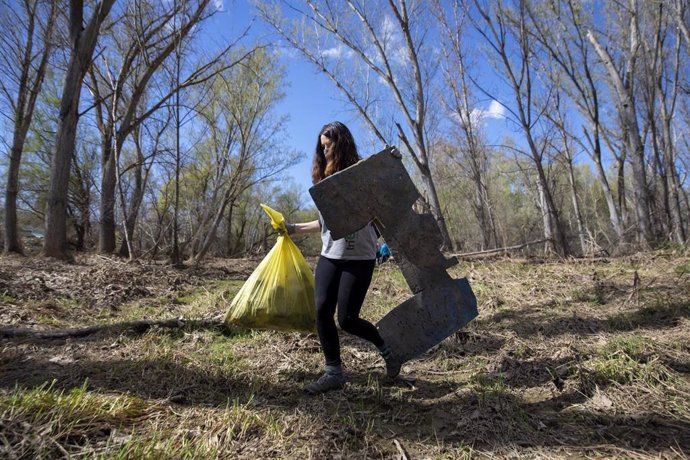 Una voluntaria transporta basura recogida en un monte.