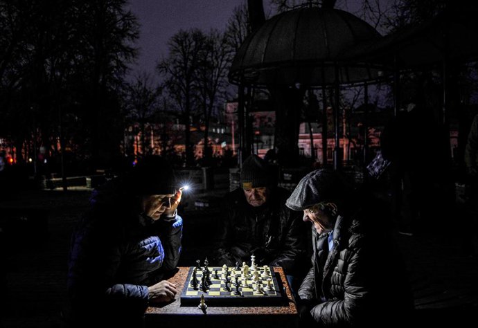 Archivo - 12 November 2022, Ukraine, Kiev: Men play chess while seeing with a flashlight at a park in Kiev. The Russian army carried out massive rocket and kamikaze drone attacks on Ukrainian energy infrastructure. According to expert estimates, 40\% of