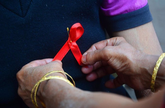 Archivo - Una persona porta el lazo rojo con motivo del Día Mundial de la Lucha contra el Sida, que se celebra el 1 de diciembre de cada año. En Calcuta (Bengala Occidental, India), a 1 de diciembre de 2020.