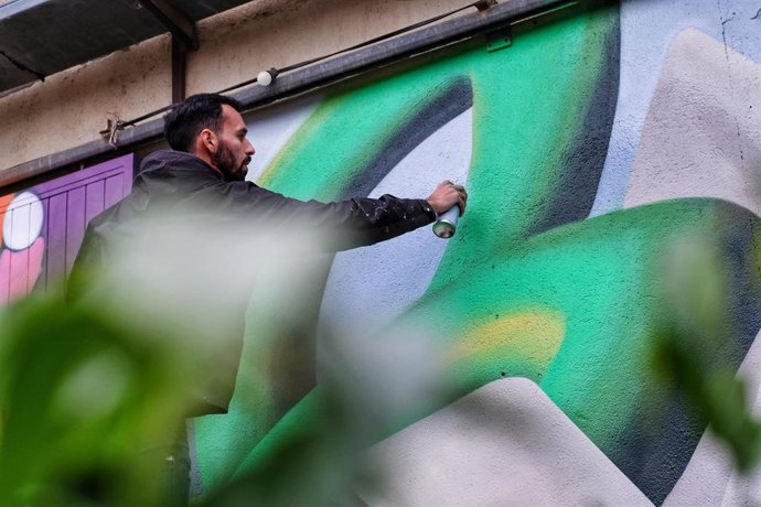 Un artista dibuja un mural con pintura de spray