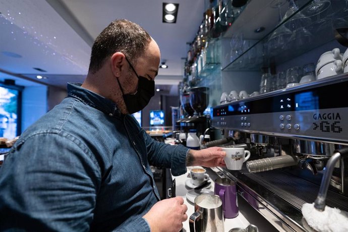 Archivo - Un camarero sirve un café en un establecimiento.