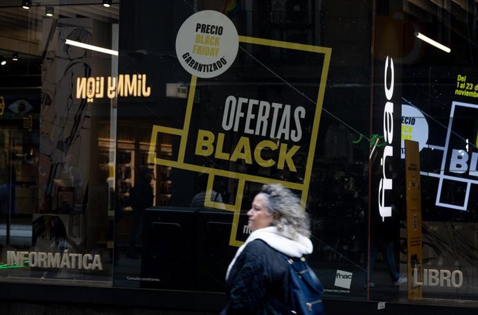 Archivo - Una persona pasa por delante de una tienda que anuncia un cartel publicitario del Black Friday'