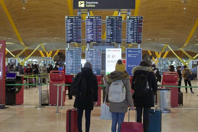 Archivo - Varios pasajeros observan los paneles indicativos de la situación de los vuelos en la terminal 4 del aeropuerto Madrid-Barajas Adolfo Suárez, en Madrid (España).