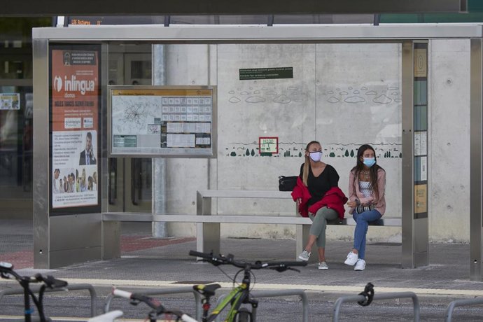Archivo - Dos estudiantes esperan sentadas en una parada de autobús de la UPNA