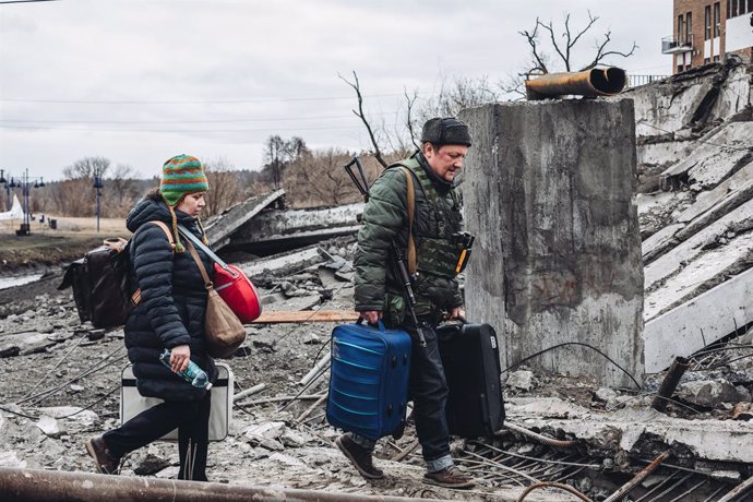 Archivo - Un voluntario armado y una mujer caminan por el puente destruido de Irpin, a 5 de marzo de 2022, en Irpin (Ucrania). El ejército de Ucrania resiste por el momento el duro asedio de Rusia a su capital, Kiev, donde se recrudecen los combates. Na