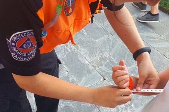 Una voluntaria colocando una pulsera identificativa.