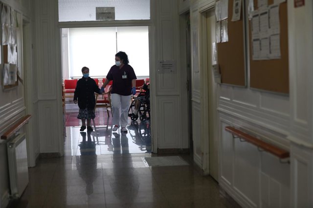 Archivo - Una cuidadora geriàtrica agafa de la mà una usuària d'una residència 