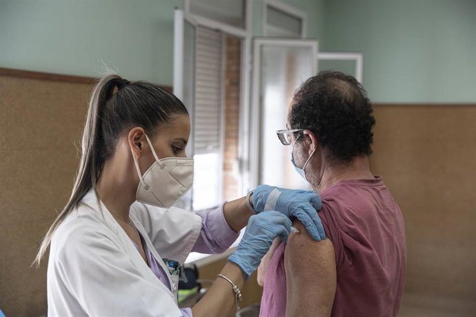 Archivo - Una enfermera vacuna a un hombre contra la gripe y el Covid. 