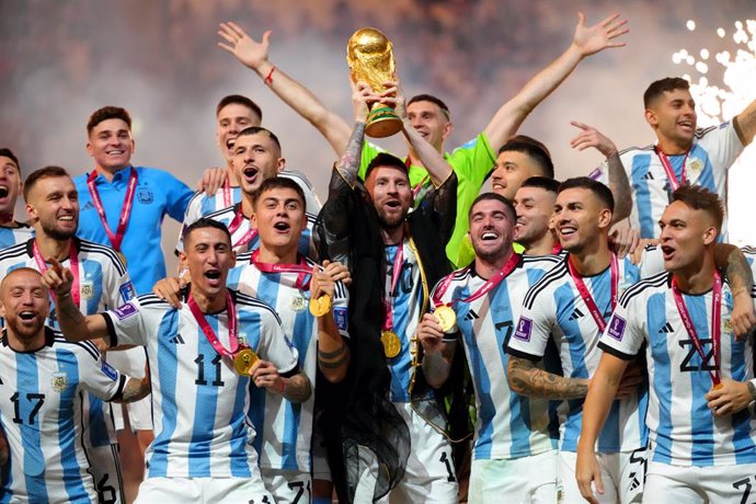 18 December 2022, Qatar, Lusail: Argentina's Lionel Messi holds up the World Cup trophy as the team celebrates after the FIFA World Cup Qatar 2022 final soccer match between Argentina and France at the Lusail Stadium. Photo: Nick Potts/PA Wire/dpa