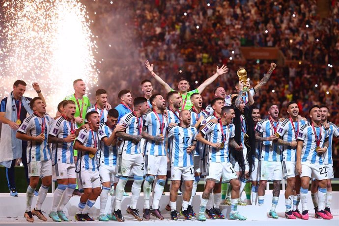 18 December 2022, Qatar, Lusail: Argentina's Lionel Messi holds up the World Cup trophy as the team celebrates after the FIFA World Cup Qatar 2022 final soccer match between Argentina and France at the Lusail Stadium. Photo: Tom Weller/dpa