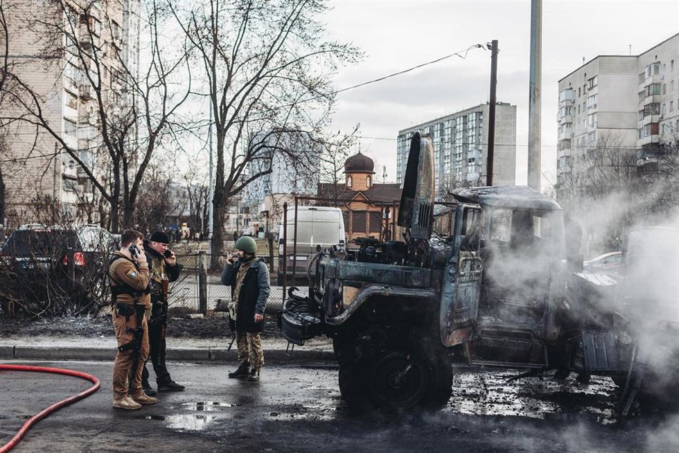Archivo - Varios soldados del ejercito ucraniano observan el vehículo militar de su ejército calcinado, a 25 de febrero de 2022, en Kiev (Ucrania).