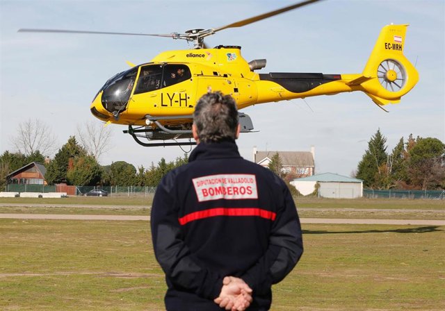 Un miembro del efectivo de Bomberos de la Diputación de Valladolid observa un helicóptero de la Junta de Castilla y León que participa en la búsqueda de un ultraligero.