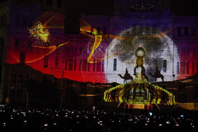 Numerosas personas observan y registran con sus móviles el espectáculo visual realizado mediante videomapping en la fachada del Ayuntamiento de Madrid