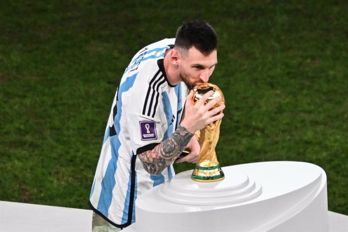 18 December 2022, Qatar, Lusail: Argentina's Lionel Messi kisses the World Cup trophy during the awards ceremony after the FIFA World Cup Qatar 2022 final soccer match between Argentina and France at the Lusail Stadium. Photo: Robert Michael/dpa