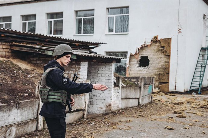 Archivo - Un policía da instrucciones frente a una guardería donde hoy ha impactado un proyectil, a 17 de febrero de 2022, en Stanitsa Luganska, Oblast de Lugansk (Ucrania). 