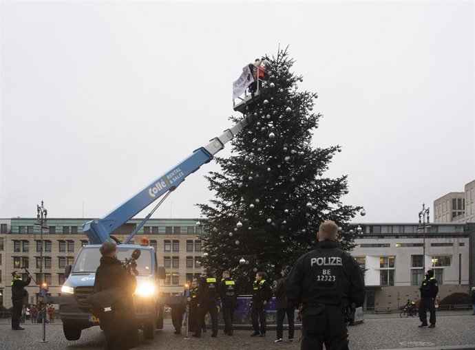 Activistas cortan la parte de arriba de un árbol de Navidad en Berlín.