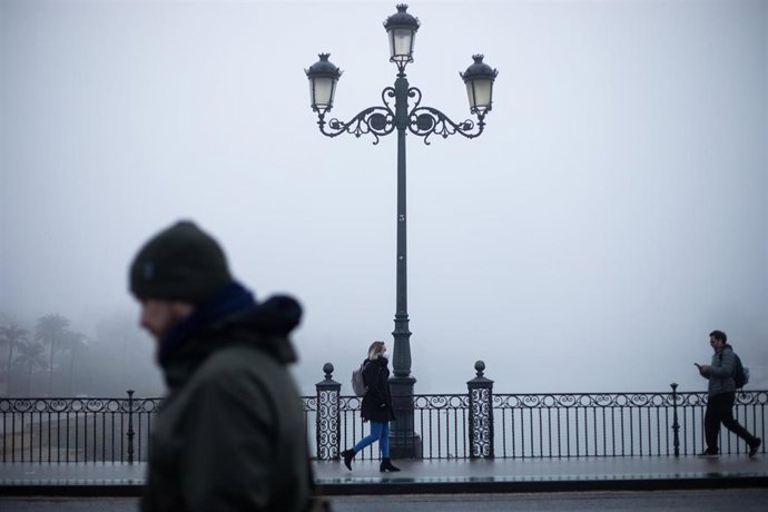 La vistas desde el Puente de Triana cubiertas por la niebla. A 21 de diciembre de 2022 en Sevilla (Andalucía, España). El solsticio de diciembre trae la estación astronómicas de invierno al  hemisferio norte de nuestro planeta. Esto sucederá el 21 de di