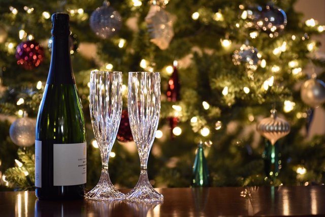 Copas y botella delante un árbol de navidad.