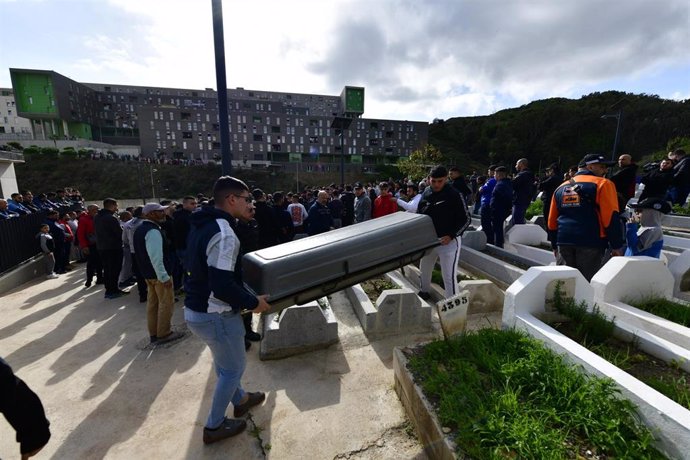 Dos personas transportan el féretro con los restos del niño de ocho años para su entierro en el cementerio musulmán Sidi Embarek, en Ceuta.