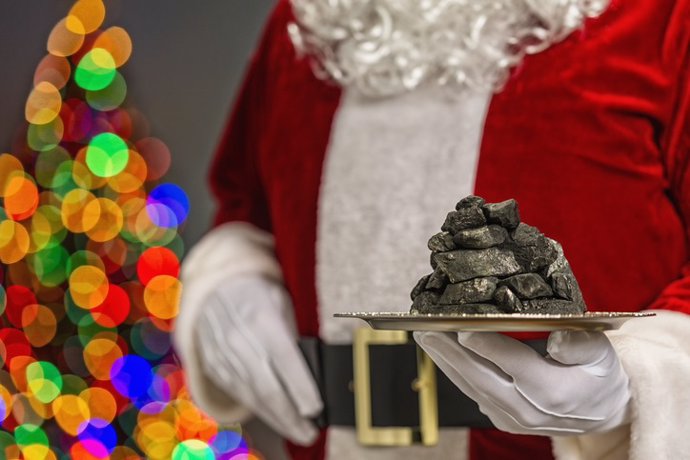 Archivo - Papá Noel sosteniendo plato de plata con una pila de carbón