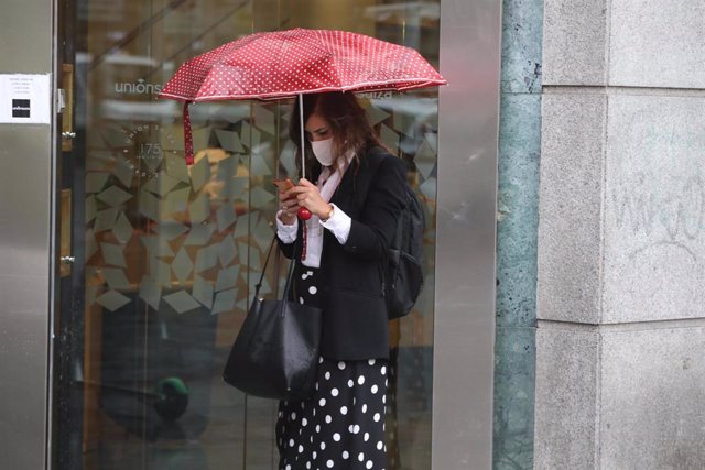 Archivo - Una mujer protegida con un paraguas 