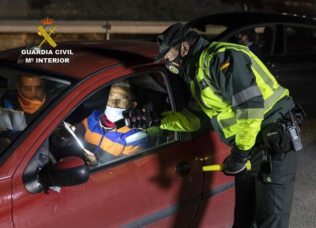 Archivo - Un agente de la Guardia Civil realiza una prueba de alcoholemia a un conductor