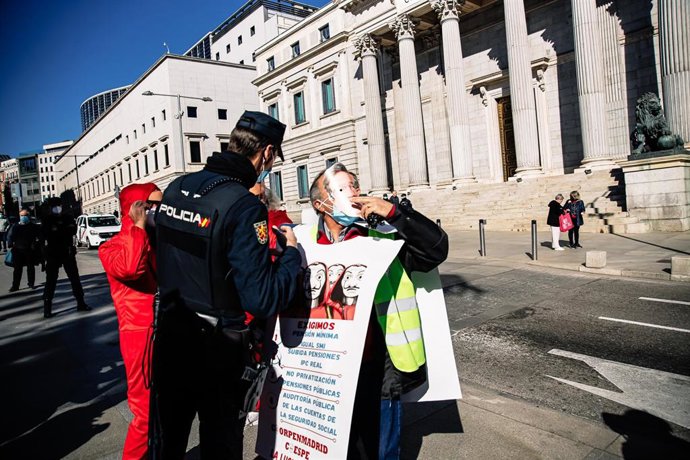 Archivo - Un agente de Policía Nacional junto a tres personas que participan en una concentración de las Plataformas y Colectivos de COORPENMADRID-COESPE, frente al Congreso de los Diputados.