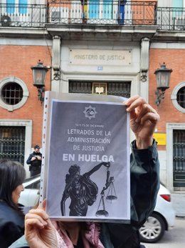 Una manifestante sujeta un cartel ante el Ministerio de Justicia en el que pide aumento salarial para los Letrados de la Administración de Justicia.