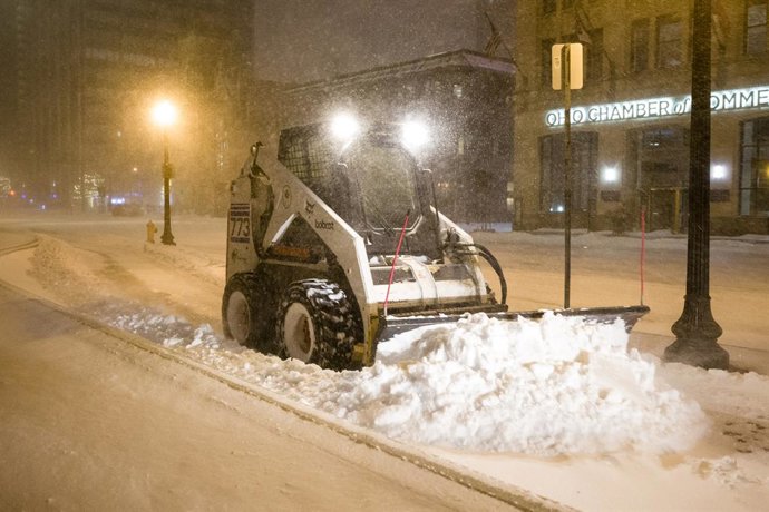 23 December 2022, US, Columbus: A skid-steer loader plows snow in front of the Ohio Statehouse as a major winter storm brings subzero temperatures across the United States. Photo: Jintak Han/ZUMA Press Wire/dpa