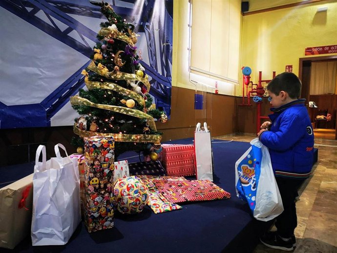 Archivo - Niño entrega regalos en la fiesta solidaria.