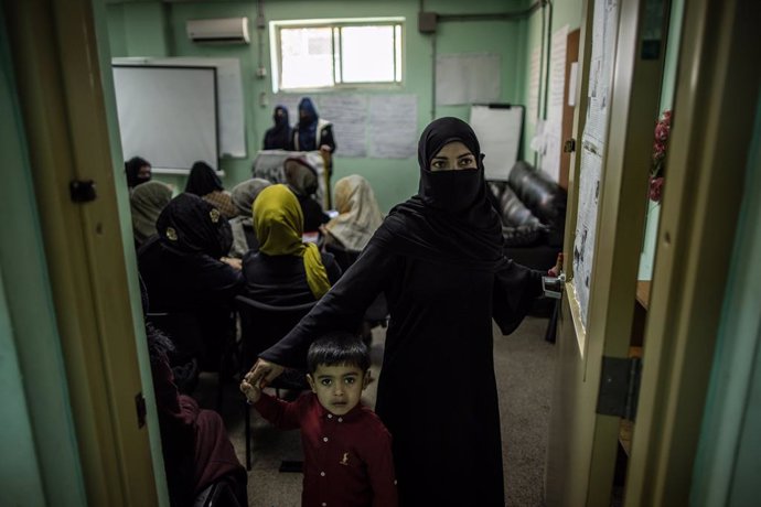 Archivo - 17 November 2022, Afghanistan, Kabul: A young woman and her son walk out of a classroom at a police barrack where women are being trained as police officers. Many of the women are the sole breadwinners for their families and must also bring th