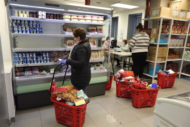 Archivo - Una persona selecciona los productos para su la cesta de compra en el interior del economato solidario de Cáritas situado en la calle Bravo Murillo de Madrid