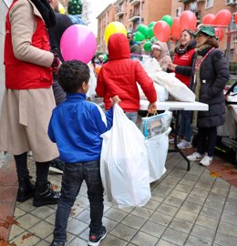 Un niño sujeta una bolsa con regalos en el reparto de regalos de la Fundación Madrina a 500 niños de familias vulnerables, en la Plaza de San Amaro, a 23 de diciembre de 2022, en Madrid (España).  