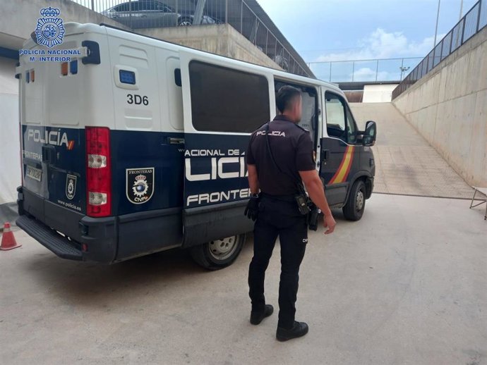 Archivo - Agente de la policía nacional junto a un furgón.