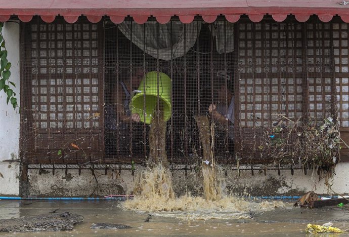 Archivo - Personas achicando agua de su vivienda en Filipinas a causa del paso de la tormenta tropical 'Nalgae'