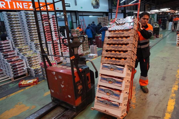 Una trabajador desplaza una carretilla con cajas.