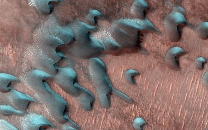 Esta imagen adquirida el 22 de julio de 2022 por el Mars Reconnaissance Orbiter de la NASA muestra dunas de arena moviéndose por el paisaje. La escarcha invernal cubre la mitad más fría de cada duna que mira al norte.