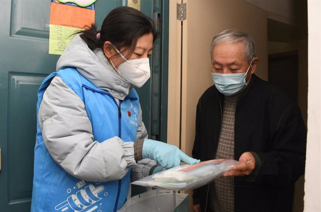 Una trabajadora entrega un paquete de asistencia en el distrito de Haidian, en Pekín